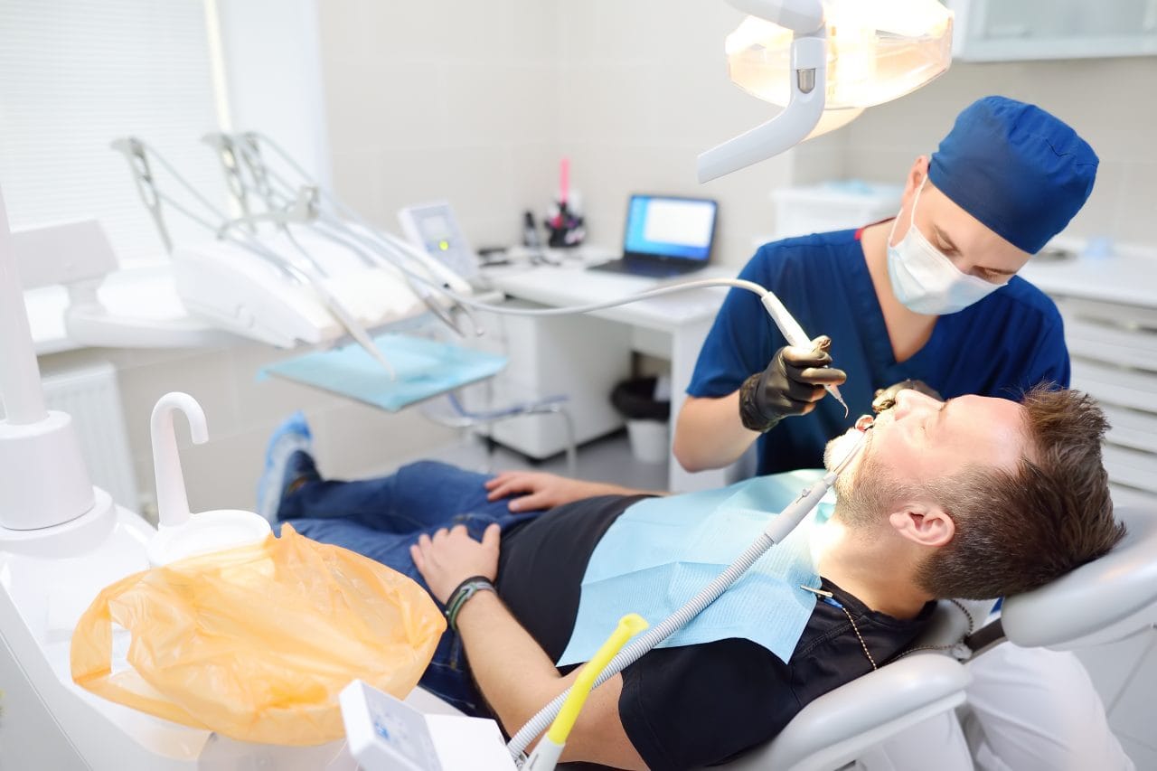 Dentist and patient at medical center. Doctor treats a mature man teeth with dental drill. Orthodontist and prosthetics appointment. Dentist and patient at medical center. Doctor treats a mature man teeth with dental drill. Orthodontist and prosthetics appointment. Hygiene and teeth healthy.